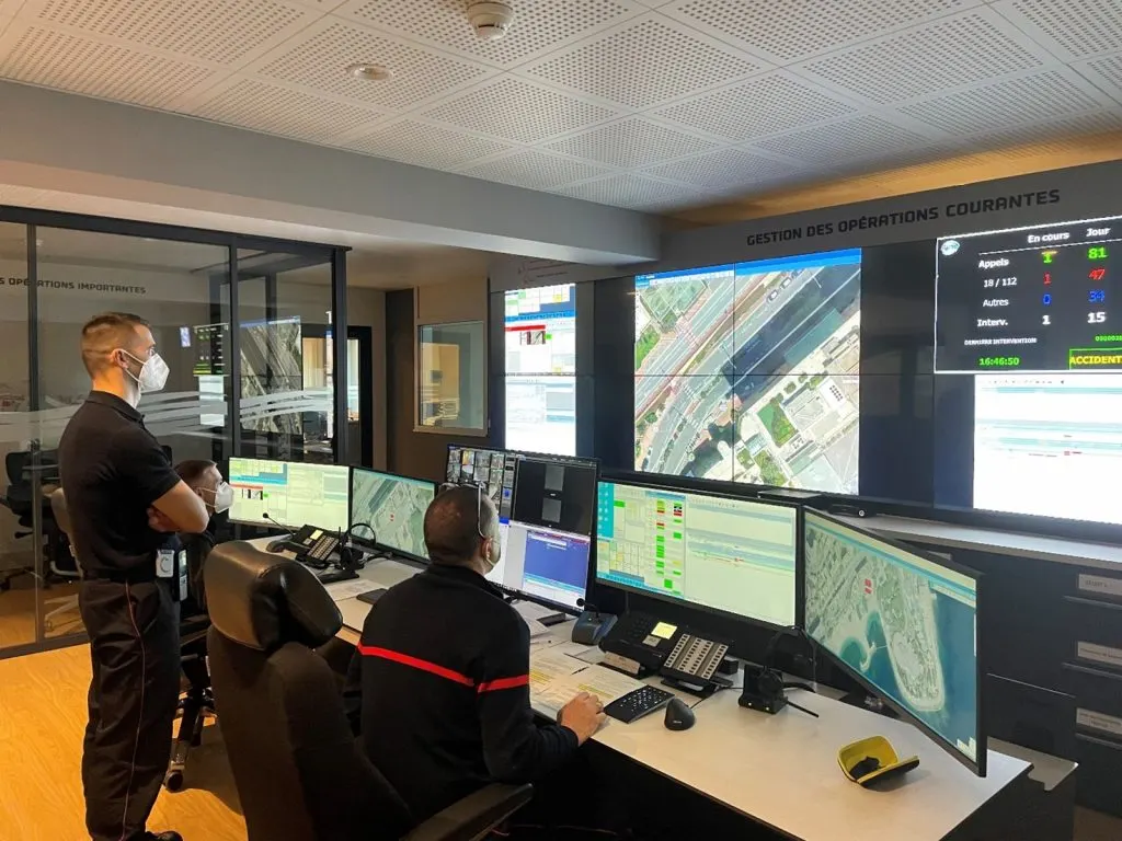 Operational management center of the Principality of Monaco, with operators in front of workstations and a video wall showing maps and live incident counts